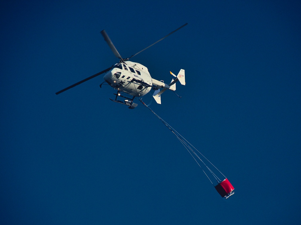 Helicopter flying with fire bucket