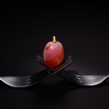 Red grape on two intertwined forks