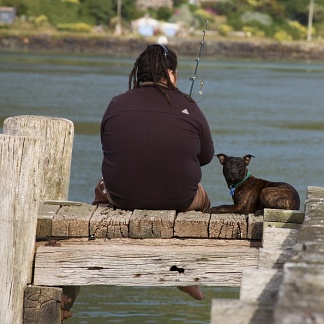 Fisherman and dog on a jetty