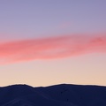 Ribbon of pink cloud above snowy mountains