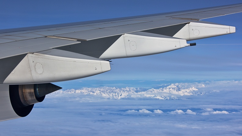 Airplane wing with jet engine and Southern Alps