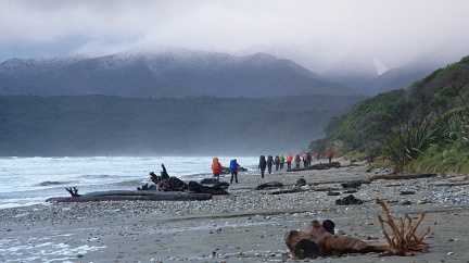 Large tramping party on the beach and snow on hills