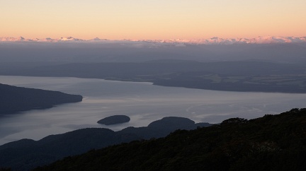 Lake Te Anau and red sunset light on snowy mountains in distance